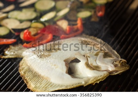 Photo closeup of delicious hot flounder with vegetables grilled fish cooked on grill charbroiled barbecue on brazier on blurred smoky background, horizontal picture
