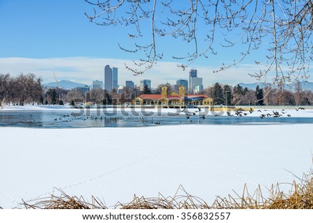 Winter Lake At Downtown Denver - A winter view of frozen lake in a city park, with city skyline and front range mountains in the background, at east-side of Downtown Denver, Colorado, USA.
