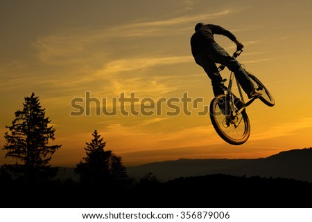Mountain bike stunt against nice sunrise and mountain silhouette in back