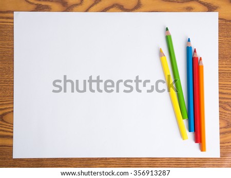 Blank white paper and color pencil on wooden table