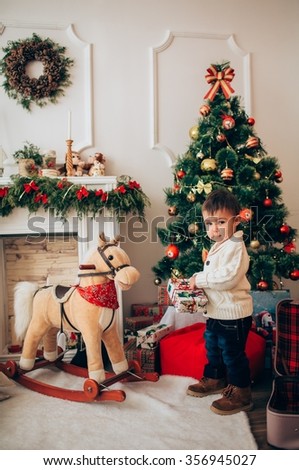 boy with toy horse near Christmas tree