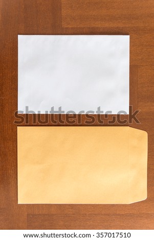 an empty white card next to  an orange paper envelop