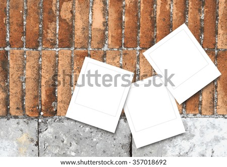 Close-up of three blank square instant photo frames on brick and stone pavement background