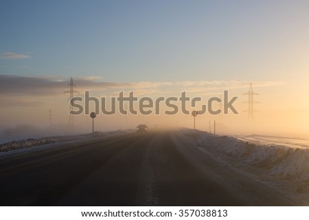 Picture of winter road and car in cold climate on sunset.