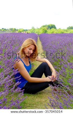 A romantic picture of a woman who is sitting between lavender rows