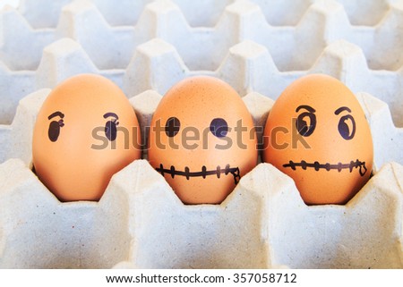 Three brown eggs with faces drawn arranged in carton