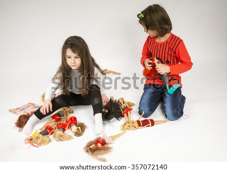 Little girls playing with dolls with light grey background 