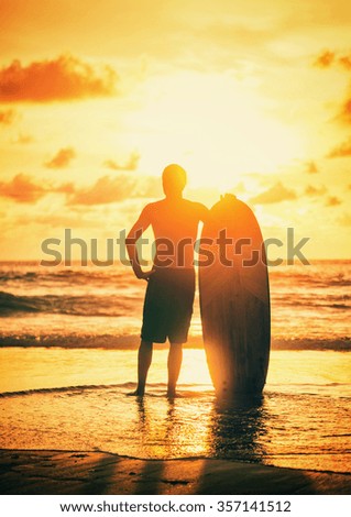 Surfer on the ocean beach at sunset on Bali island, Indonesia -  intentional noise