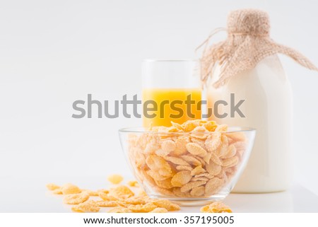 Perfect breakfast. Bottle of milk for cornflakes and glassful of fresh orange juice are on white surface.