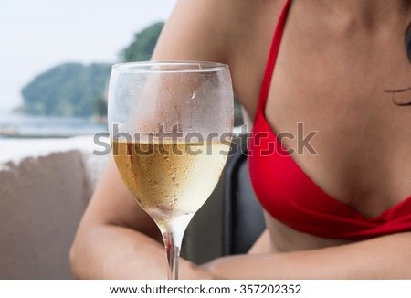 Lady in red bikini with glass of champagne in outdoors restaurant