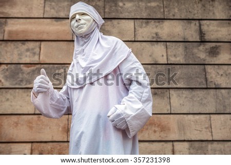 Street performance of actor stylized in white clothes and mask.