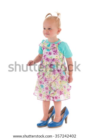 Toddler girl standing inmothers big shoes isolated over white background