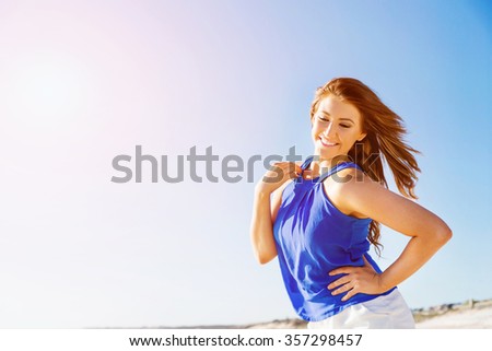 Portrait of young pretty woman walking along sandy beach
