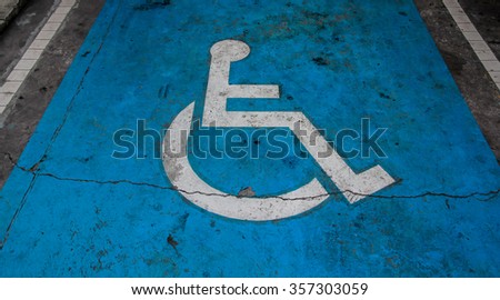 International handicapped symbol painted in bright blue on a shopping center parking space. 