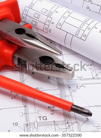 Rolls of electrical diagrams with work tools lying on construction drawing of house, drawings for the projects engineer jobs