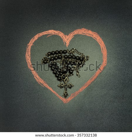 in the picture a rosary iron at the center of a heart drawn with a crayon,square photo.