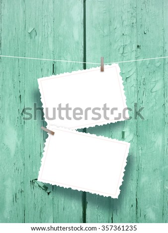 Close-up of two hanged postcards with pegs on weathered wood background