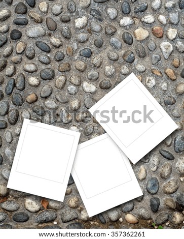 Close-up of three square instant photo frames on pebble pavement background