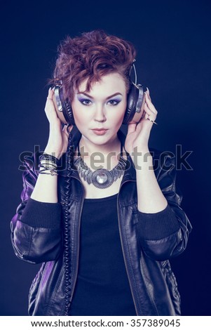 Beautiful young girl with headphones on a dark background