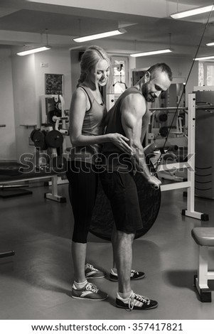 Sport couple on training in the gym. Healthy life. Help and support when performing exercises. Photos for sporting magazines and websites. 