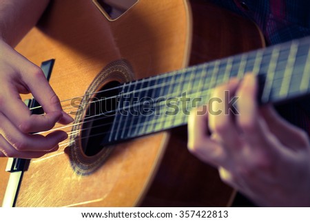 Young man playing acoustic guitar during a concert. - Vintage colours.