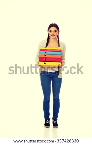 Happy teen woman holding binders.