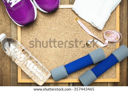 Fitness and sport equipment : sneakers,towel,bottle of water with wooden background on top view