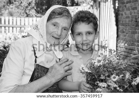 Summer in the garden on a sunny day with a grandmother grandson boy holding a bouquet of wildflowers. Black and white photo.