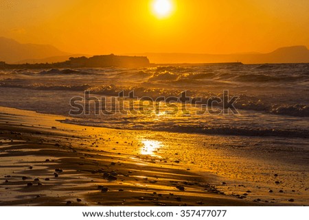 A beautiful beach on a Greek island in summer, under warm sunset light