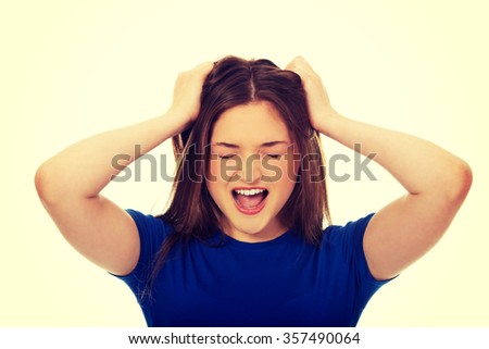 Angry teenage woman holding her head.