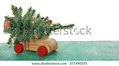 Wooden toy car with Christmas tree on a table over white background