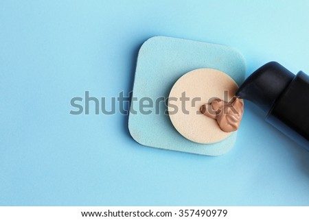 Makeup sponge with liquid foundation on blue background