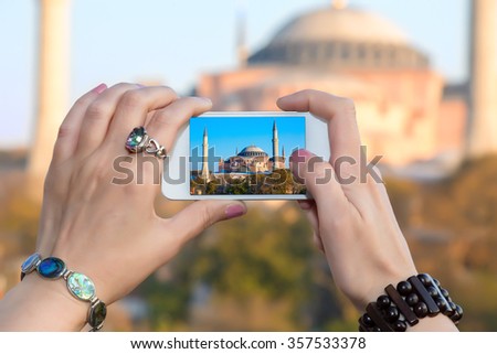 Woman taking Photo with camera phone in Istanbul city female hands with fashion bracelets  holding white telephone with Picture of famous attraction view