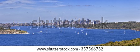 panorama of entrance to Sydney harbour from North head towards south head with lighthouse and further yachts and boats in front of city CBD on a sunny day