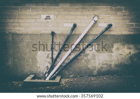 A photo of black and white angular water pipes on a beige brickwork wall with a strong vintage filter