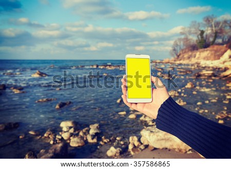 White smart phone on the background Black Sea in female hands, instagram effect