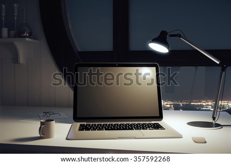 Black blank laptop with cup of coffee and lamp at night
