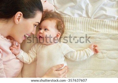 happy family. mother playing with her baby in the bedroom.