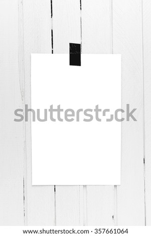 Blank white poster hanging on a tape on white wooden plank wall. Template background for your design.