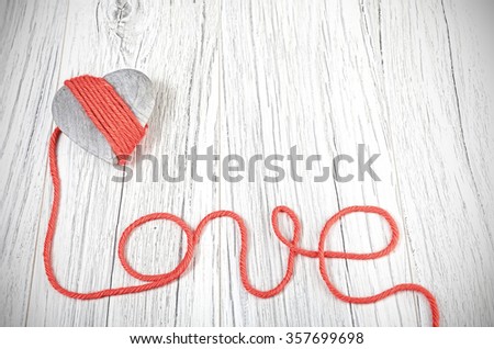 Wooden heart with red yarn love sign, space for text.