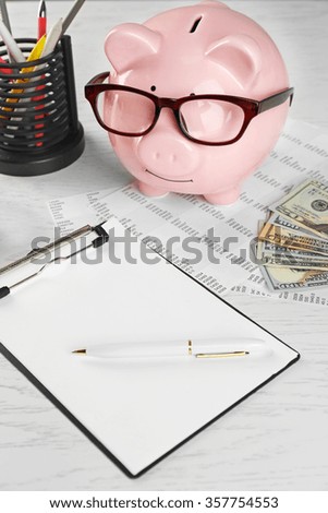 Bookkeeping concept. Piggy bank, calculator, dollars and papers on white wooden background