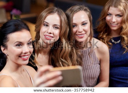 women with smartphone taking selfie at night club