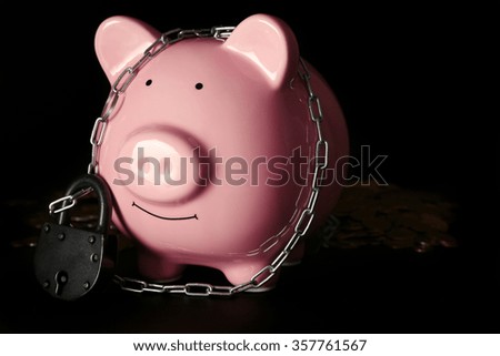 Piggy bank and chains on dark background