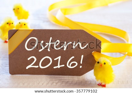 One Brown Label With Yellow Ribbon. German Text Ostern 2016 Means Happy Easter. Card For Easter Greetings On Wooden Background