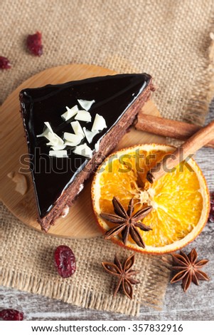 Dark chocolate cake on wooden rustic background. Cinnamon and spices. Dried orange. Sweets and diet.