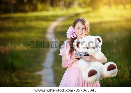The nine-year girl in a pink dress is going to take pictures teddy bear