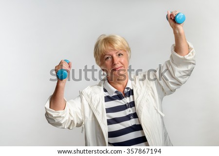 Grandma does physical exercises with dumbbells