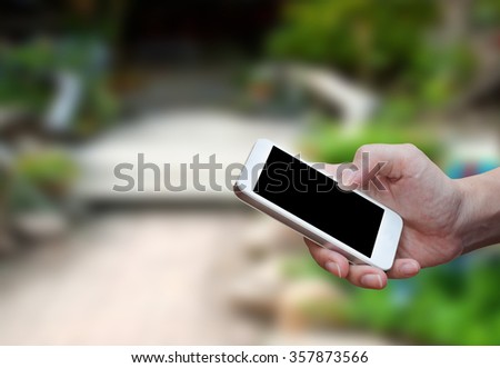 Man's hand shows mobile smartphone in vertical position, blurred background - mockup template
