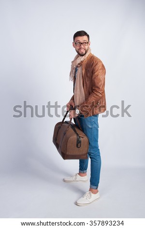 A young man in a brown jacket with a travel bag