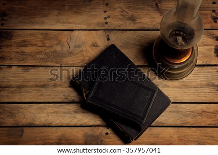 old vintage book's on a wooden table by kerosene lamp, candlelight, picture from above
